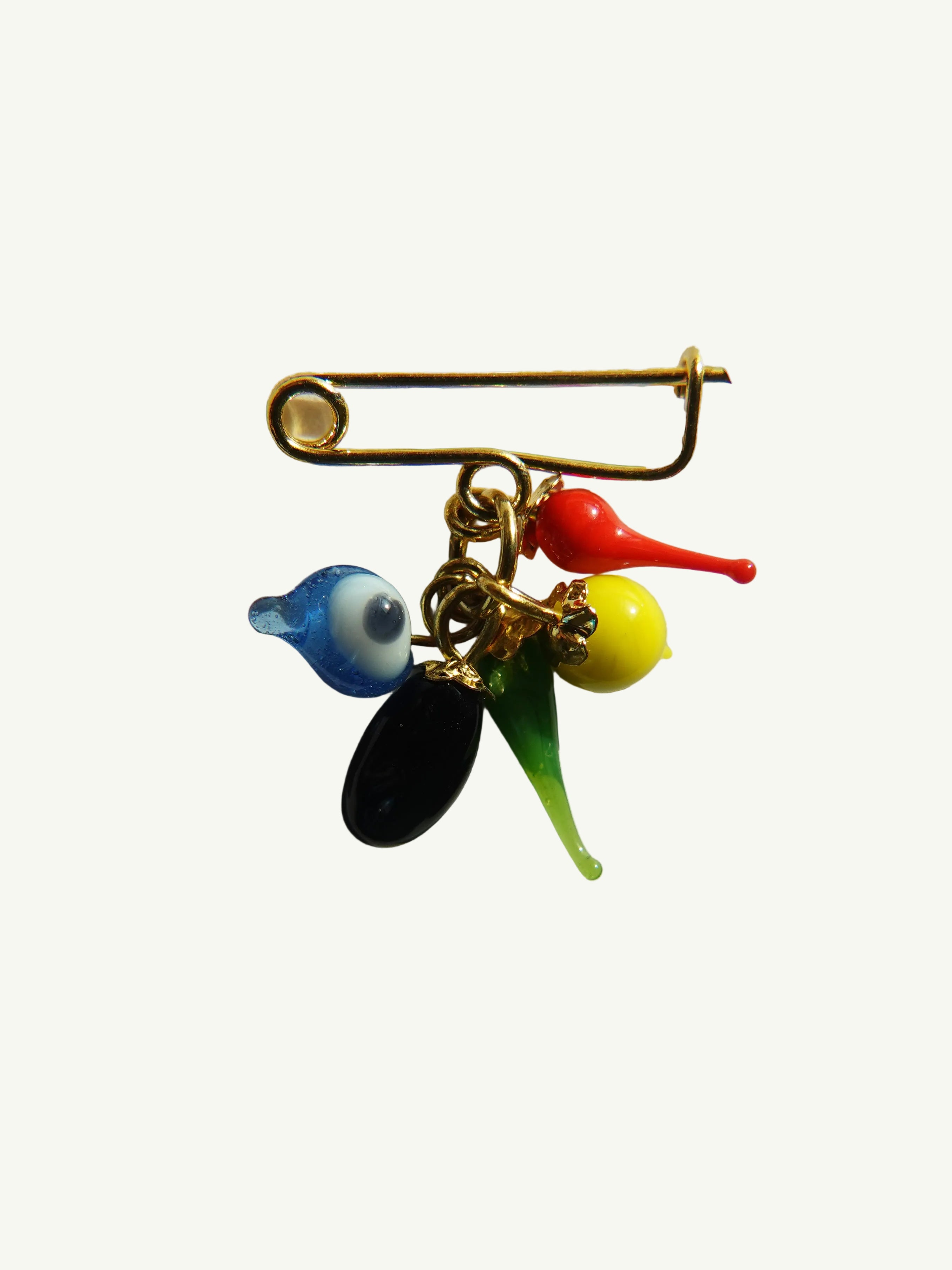 A vintage Nazar brooch featuring a multi-colored design with representations of an eye, a tomato, a pepper, a lemon, and an eggplant.